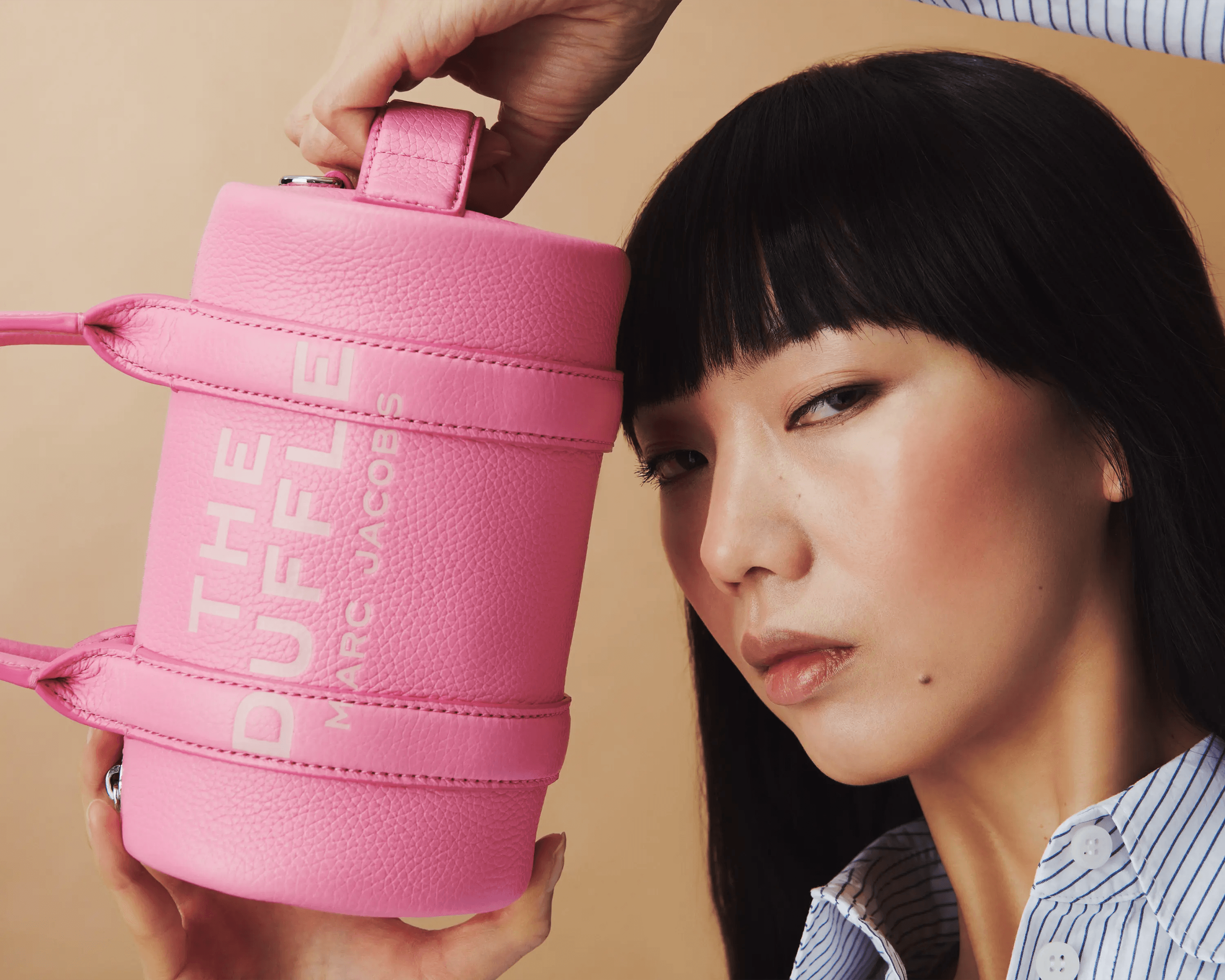 female model pressing pink Marc Jacobs The Duffle bag to cheek, intimate close up, luxury accessories campaign photography London