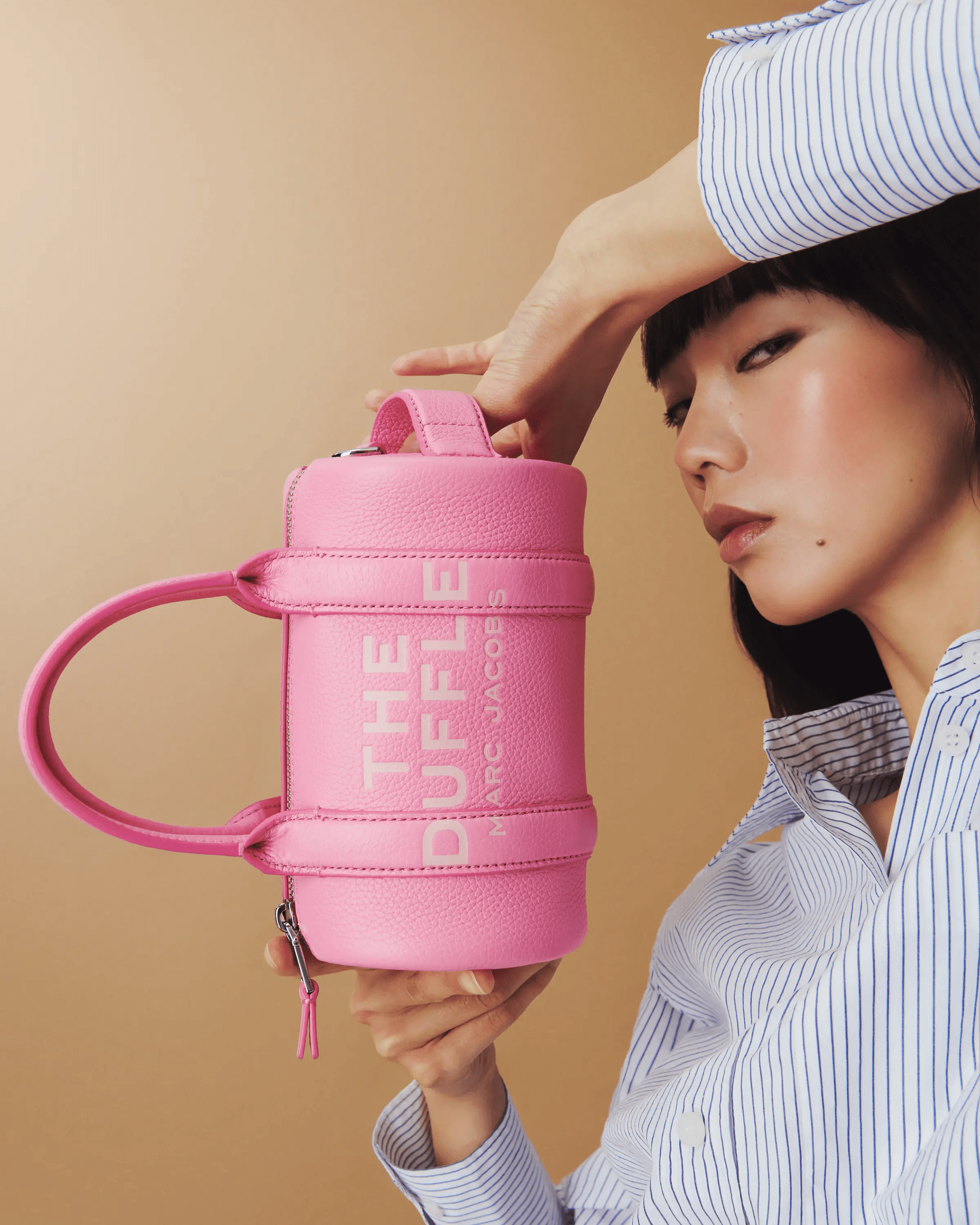close up product portrait of pink Marc Jacobs The Duffle bag held in both hands, luxury accessories campaign photography London