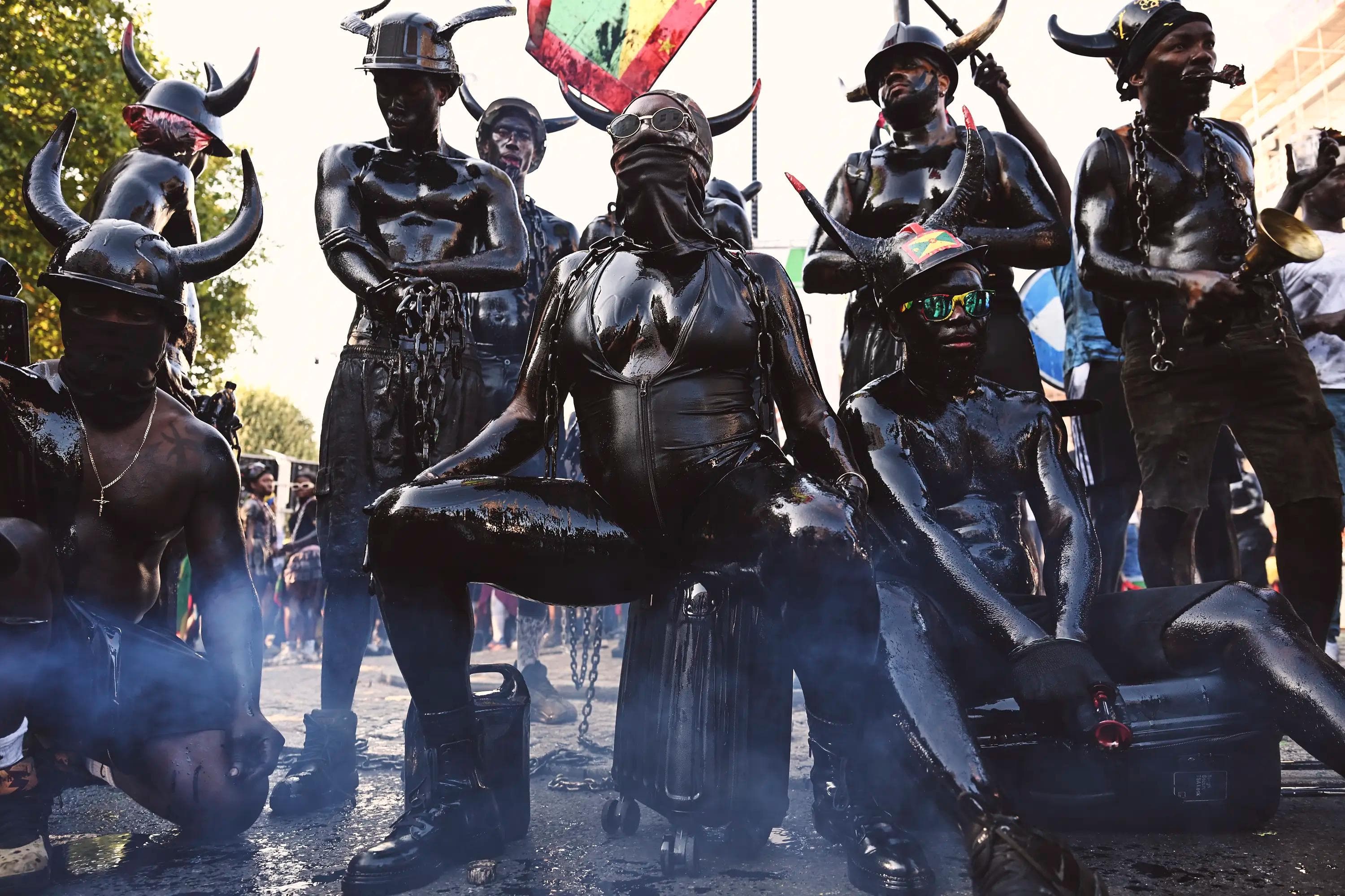 staged group portrait of Jab Jab performers sitting in smoke during carnival celebration