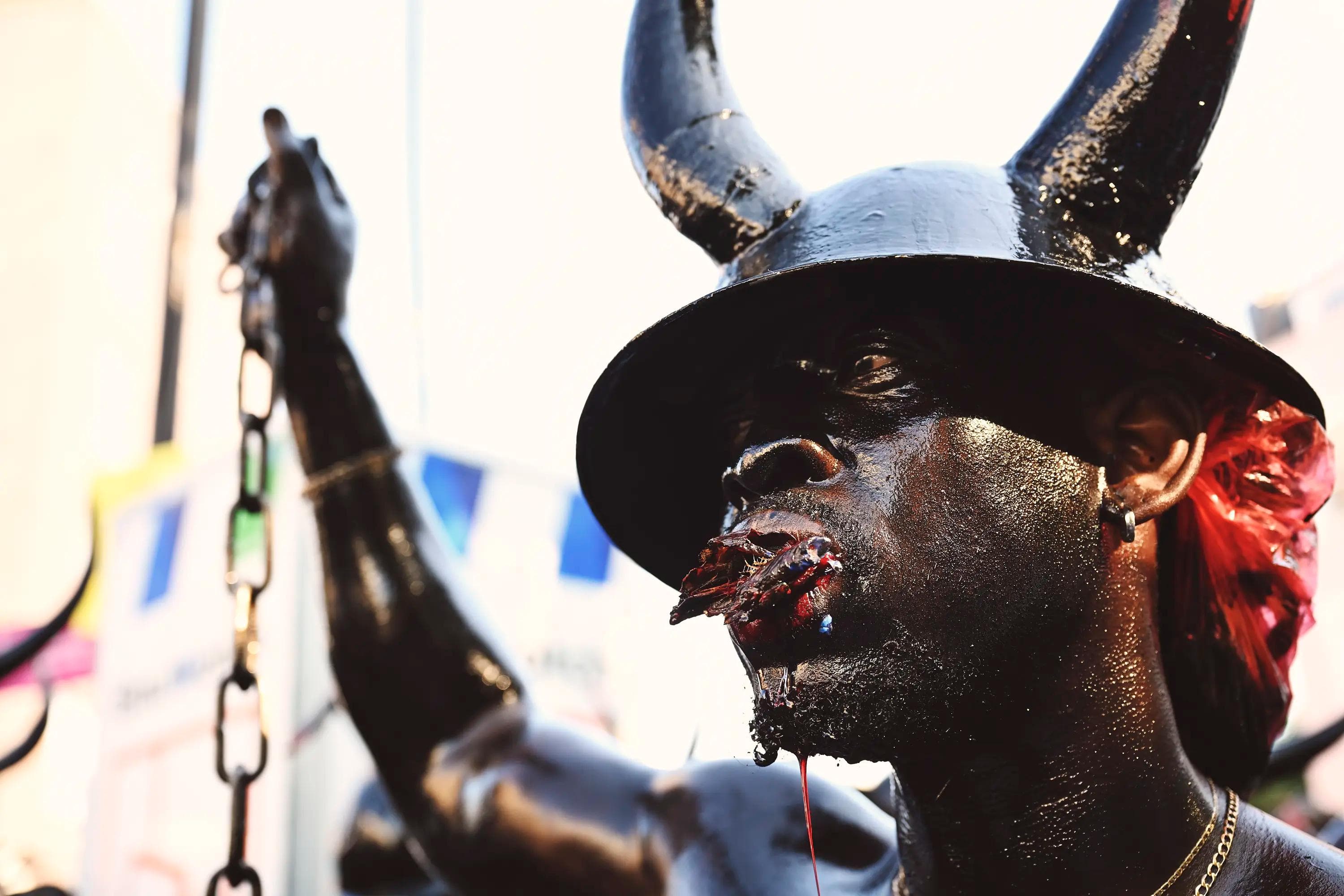 close portrait of Jab Jab participant with horned helmet and chains during Caribbean carnival tradition