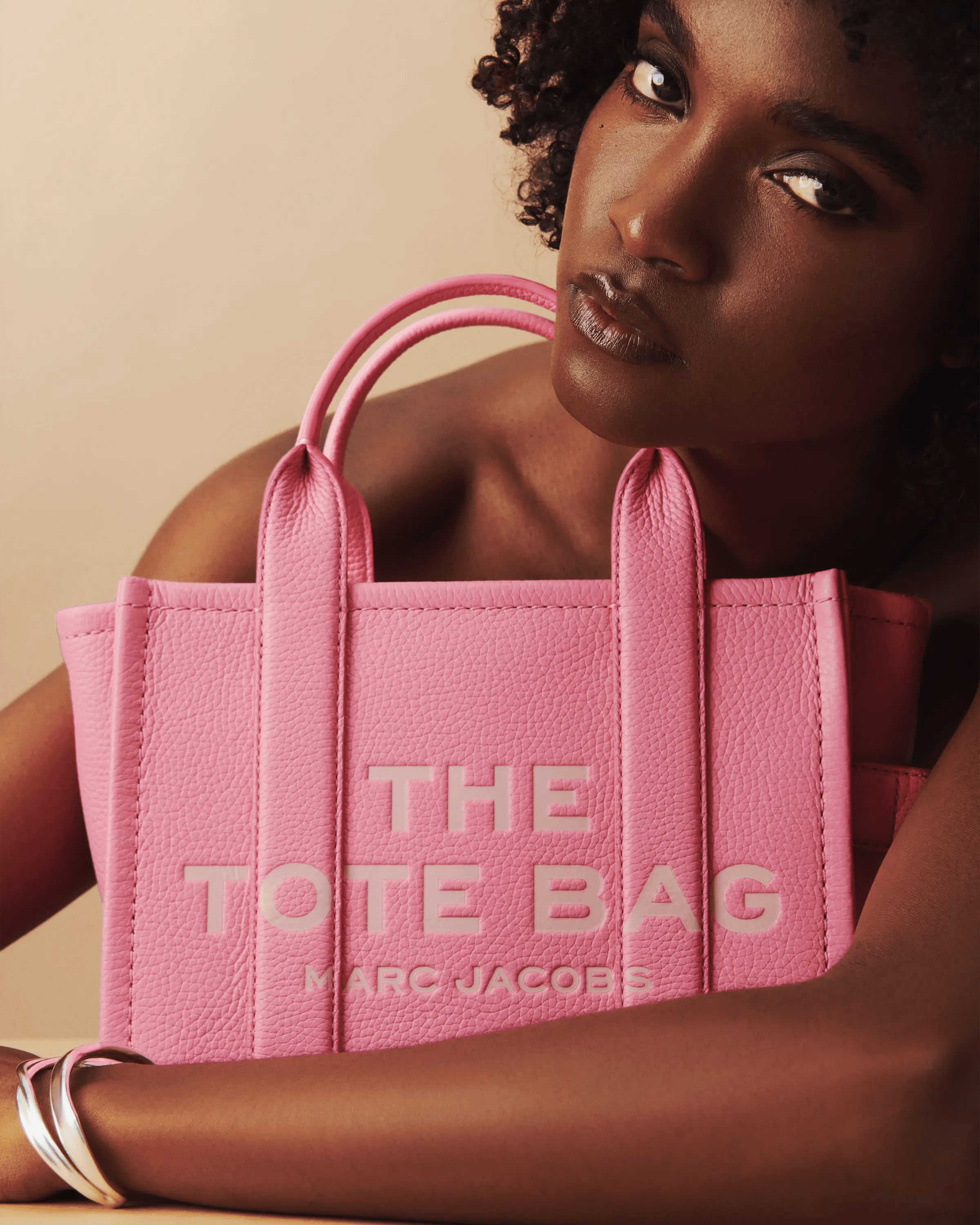 female model holding pink Marc Jacobs The Tote Bag with direct gaze, controlled studio portrait, editorial fashion photography London