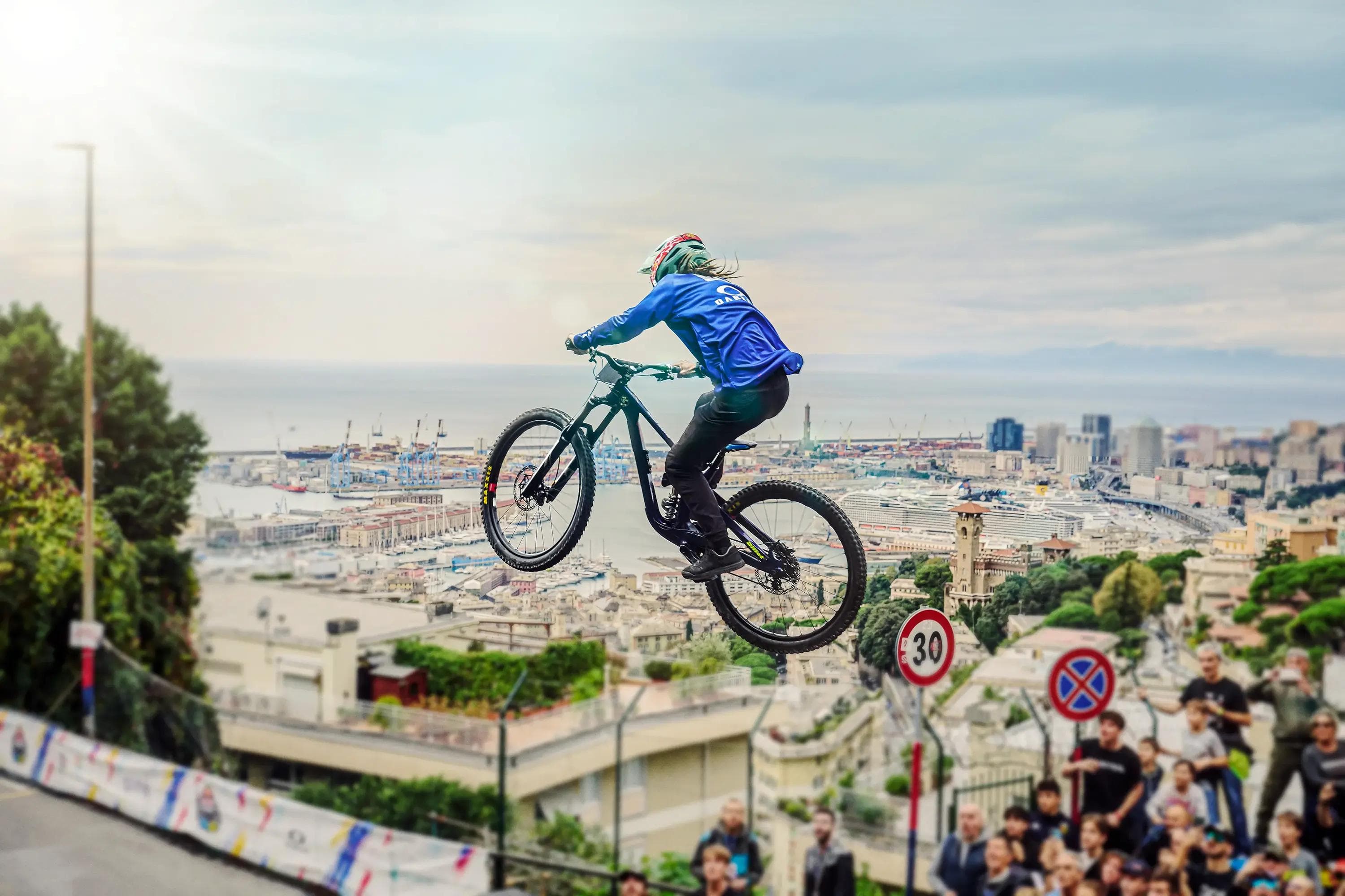 mountain biker jumping over cityscape with harbour in background, wide angle, extreme sports photography