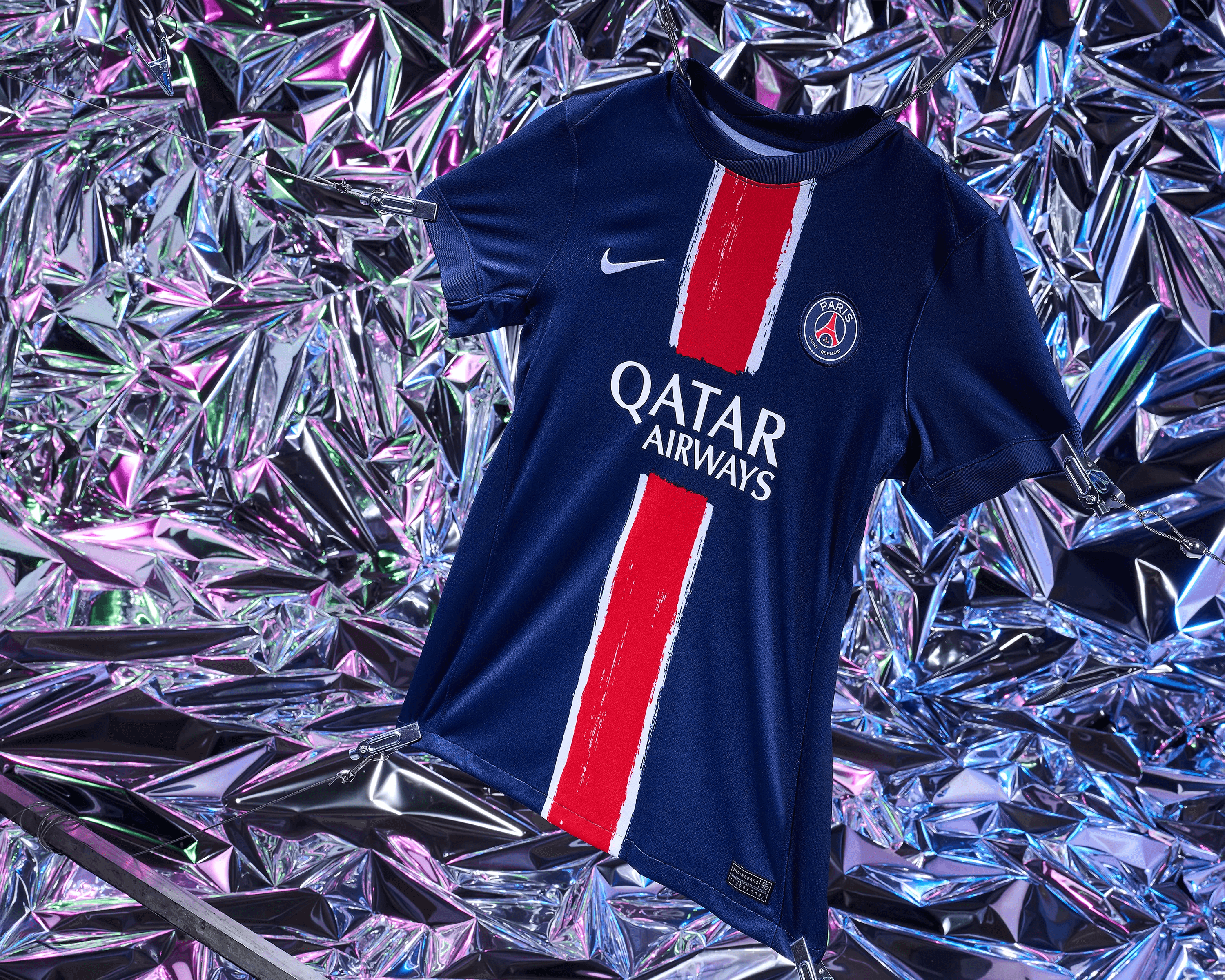 close detail of PSG kit hem with engineered label and metal clip against holographic backdrop, sportswear product photography Manchester