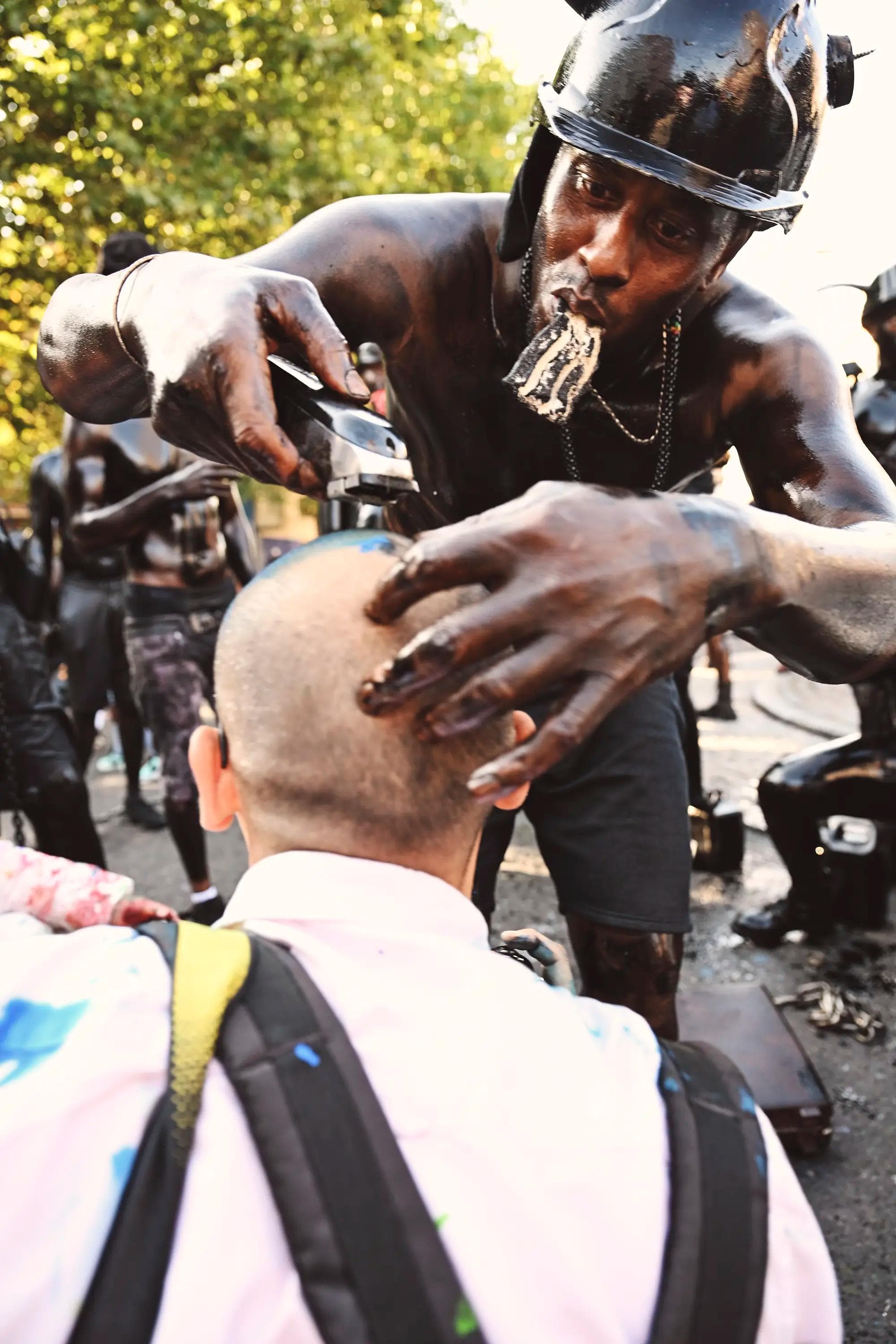 carnival performer pretending to shave spectator's head during Jab Jab street performance