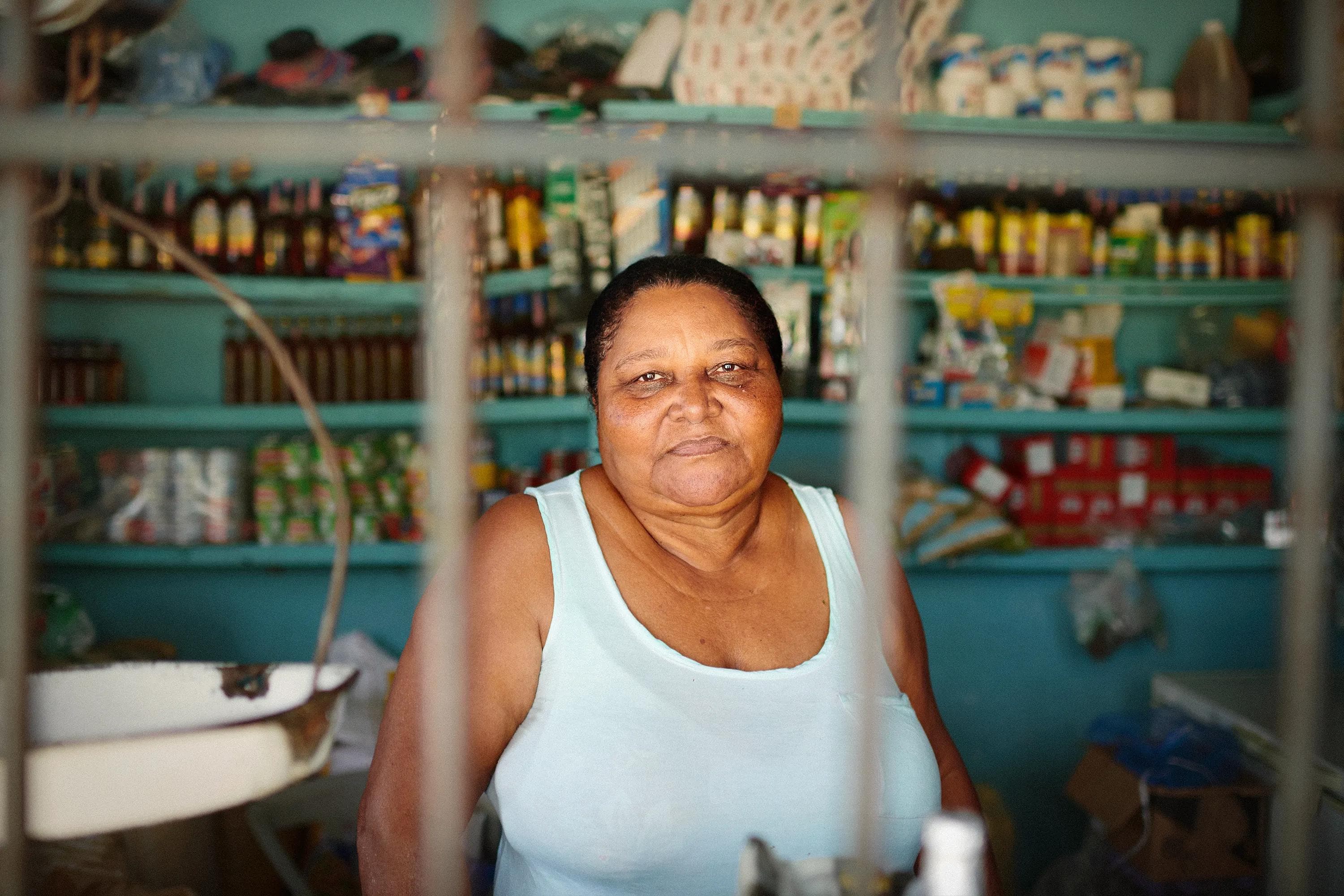 elderly woman in bright pink dress leaning on balcony in rural Dominican Republic, natural light portrait