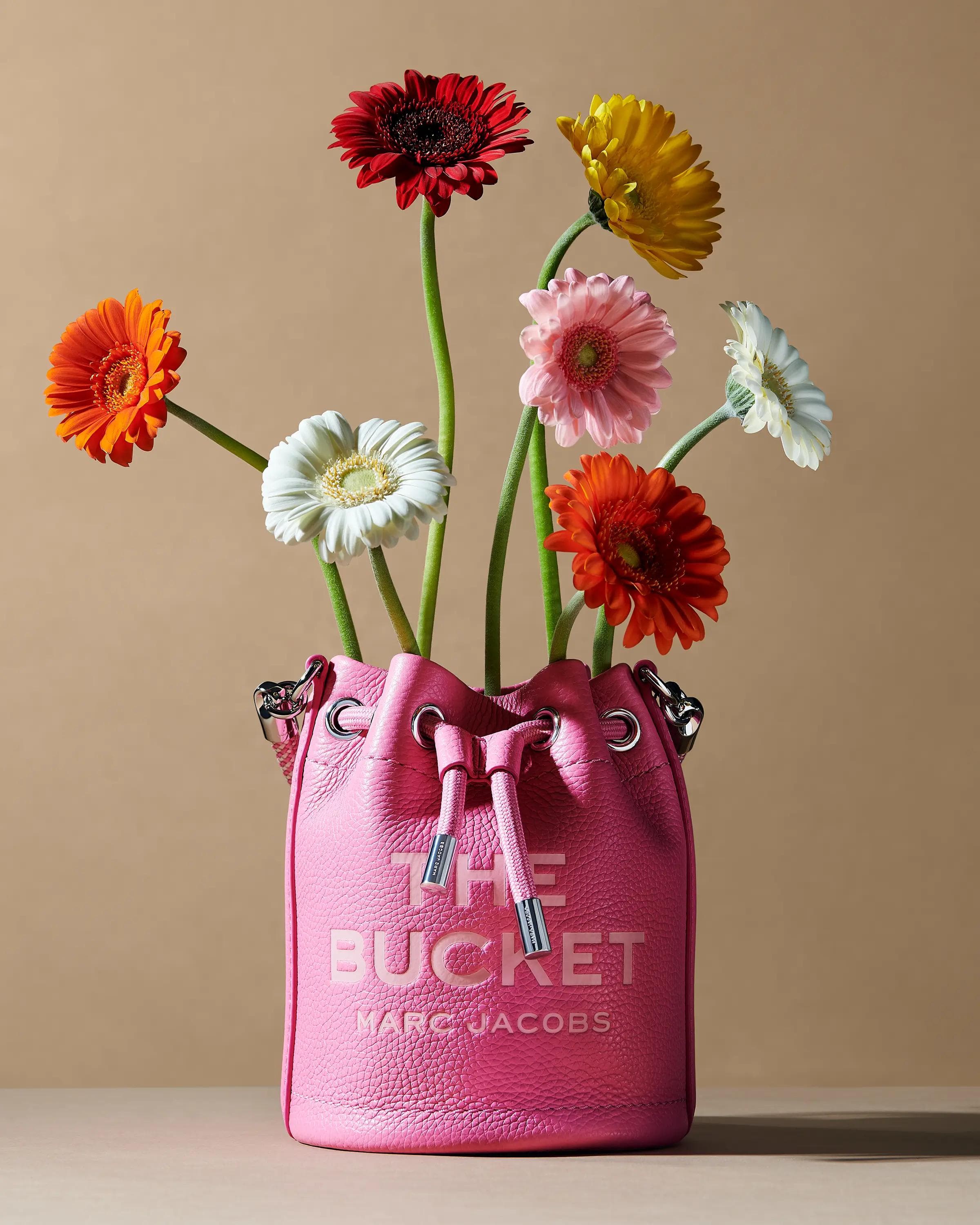 close detail of pink Marc Jacobs The Duffle bag leather texture and embossed logo with tulip stem and flower, luxury product photography London