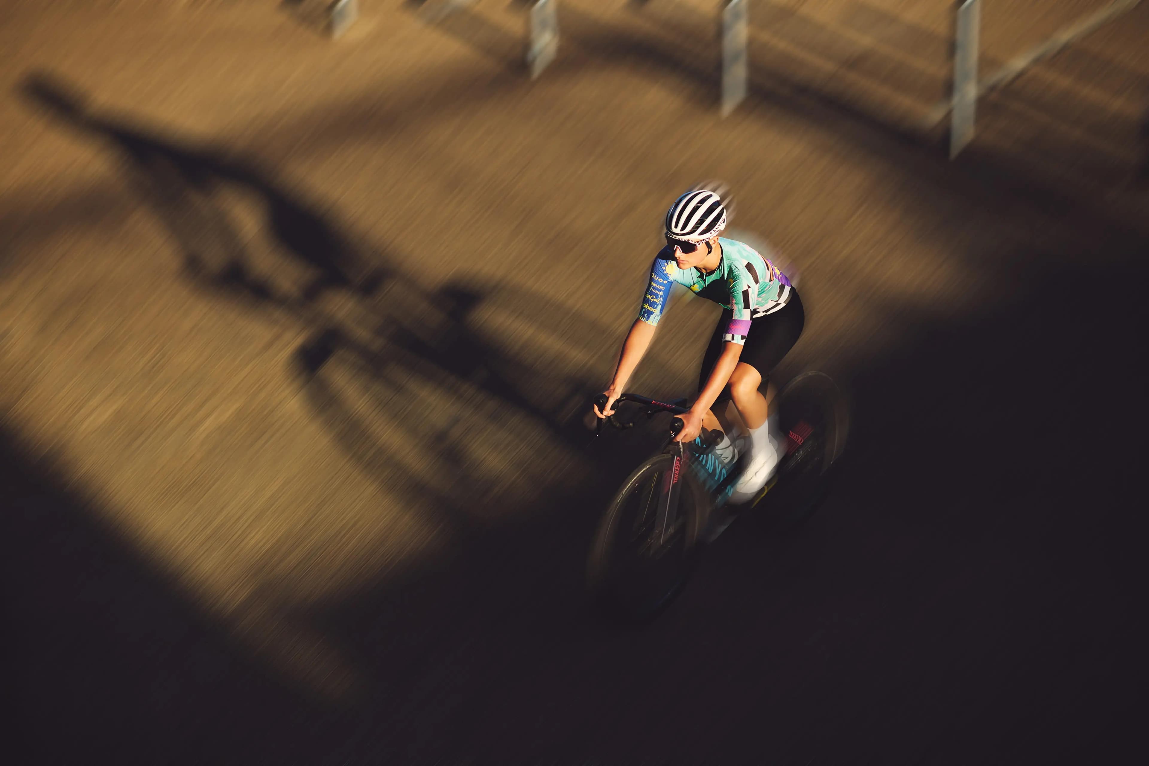 athlete holding road bike over shoulder with sun flare, performance cycling photography London
