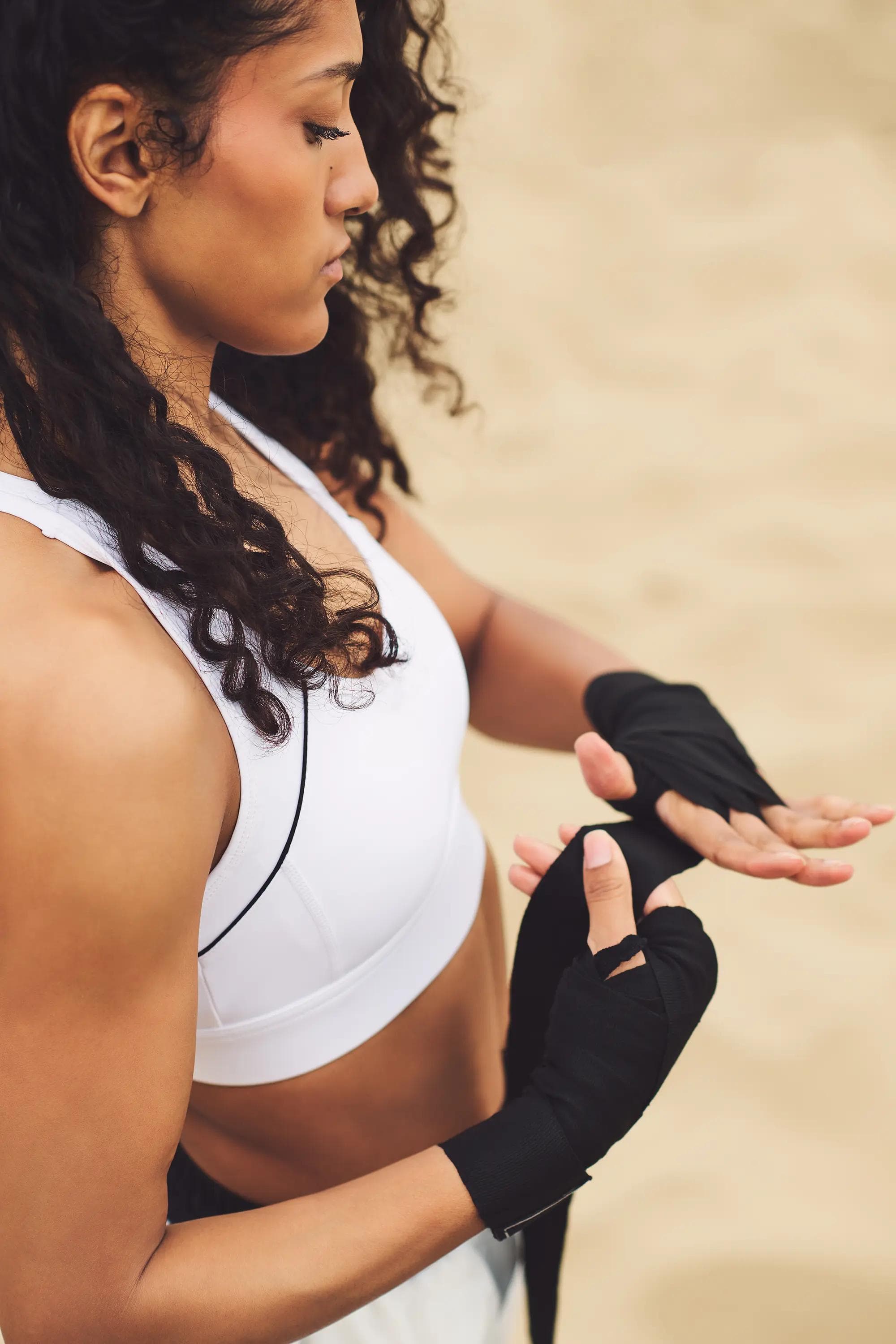 close up of female athlete wrapping black boxing hand wraps during outdoor beach training