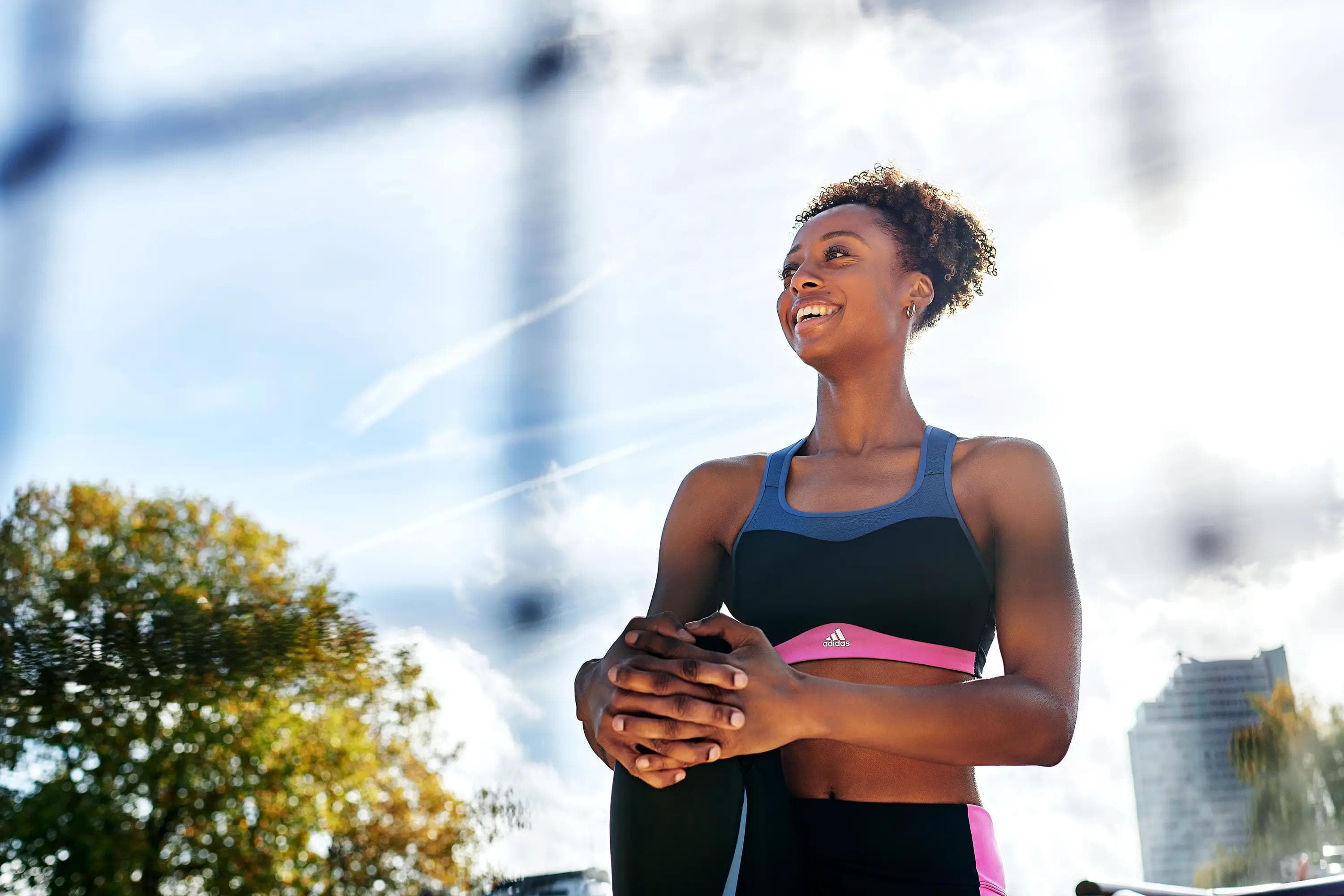 female athlete stretching outdoors in adidas activewear beneath bright sunlight, fitness lifestyle photography