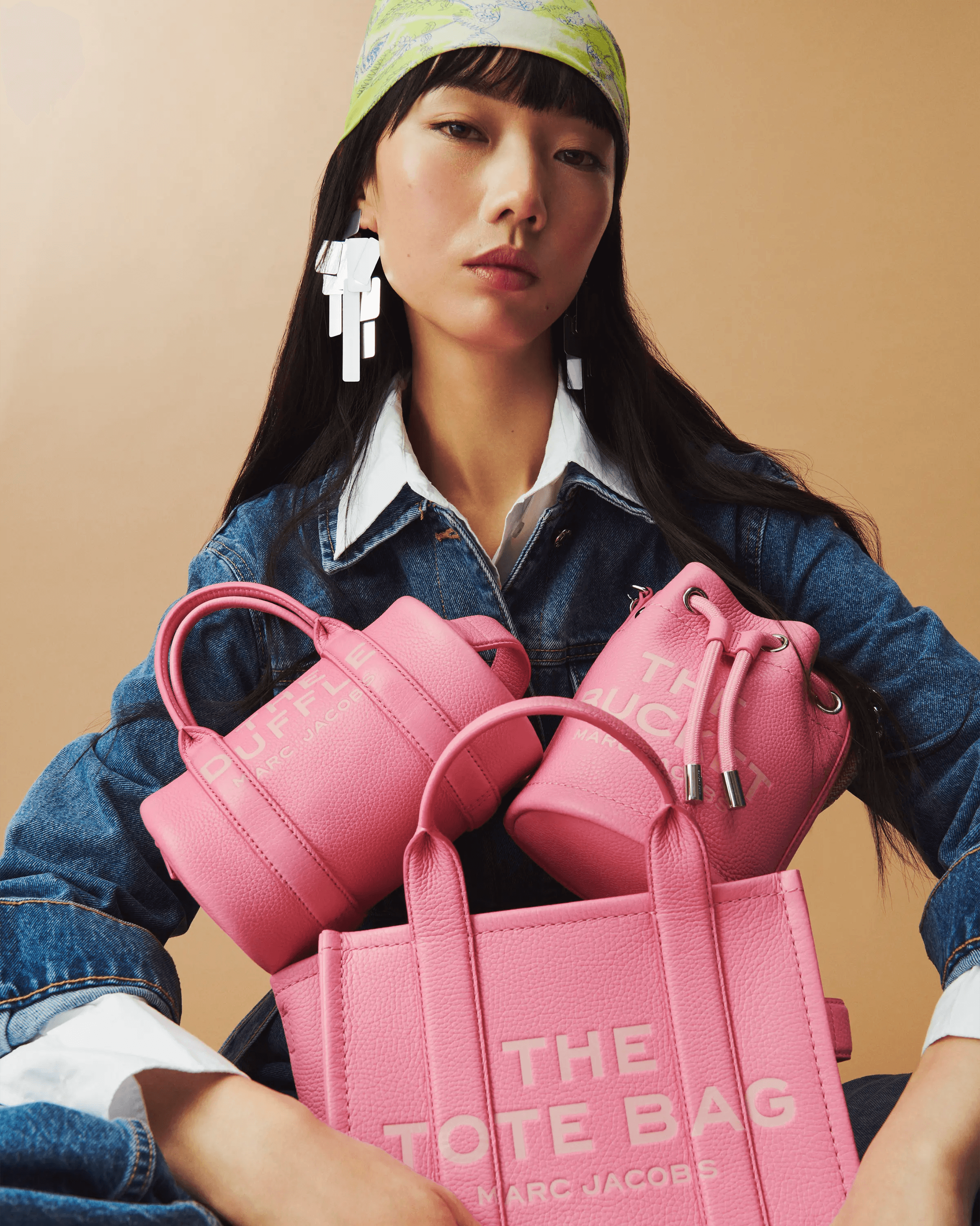 female model in denim jacket holding Marc Jacobs Tote, Duffle and Bucket bags in pink, full collection editorial, studio fashion photography London