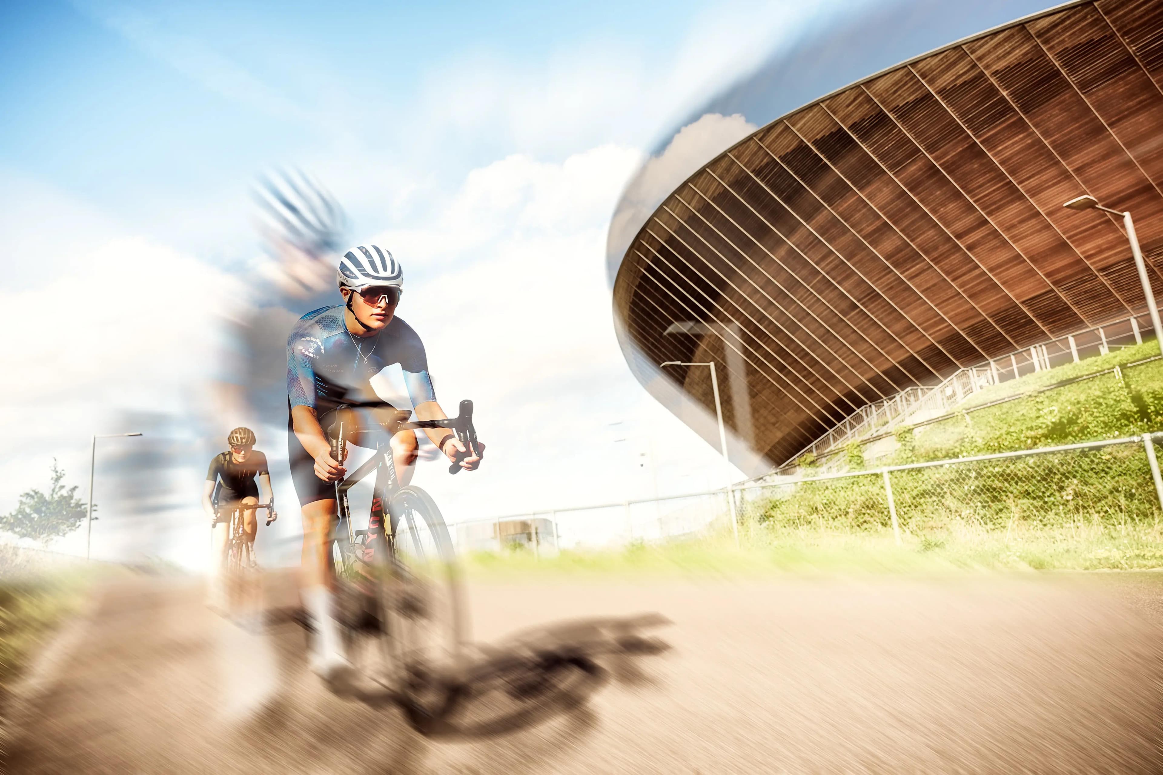 cyclist standing with road bike against minimal wall with strong sunlight and shadows, sports photography London