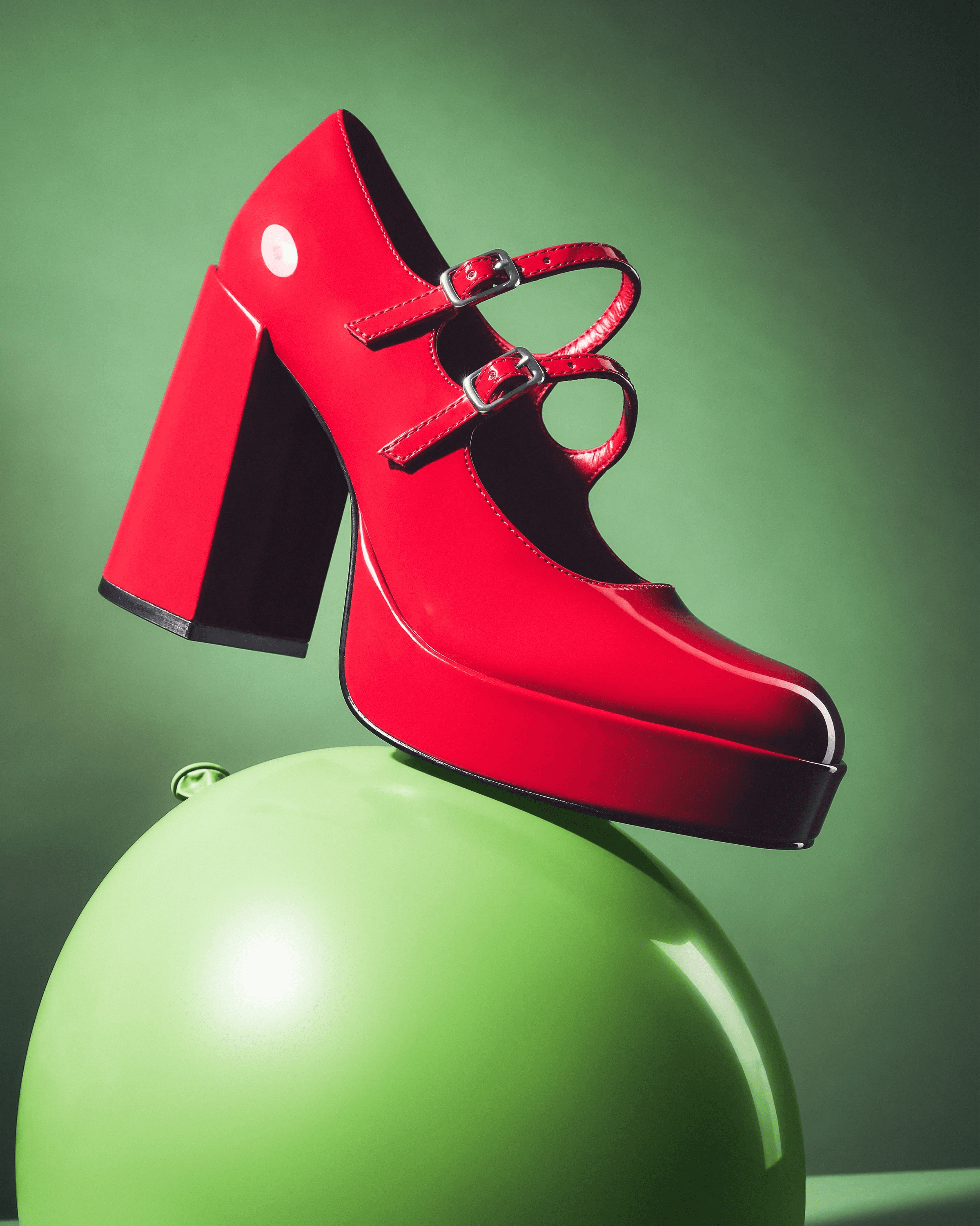 red patent Steve Madden Mary Jane shoe leaning against inflated red balloon, bold colour still life campaign photography London